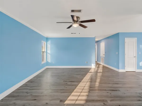 a view of empty room with wooden floor and fan