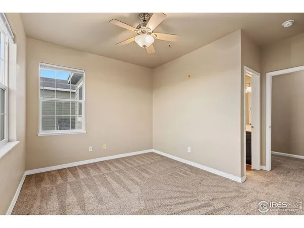 a view of an empty room with a window and a ceiling fan