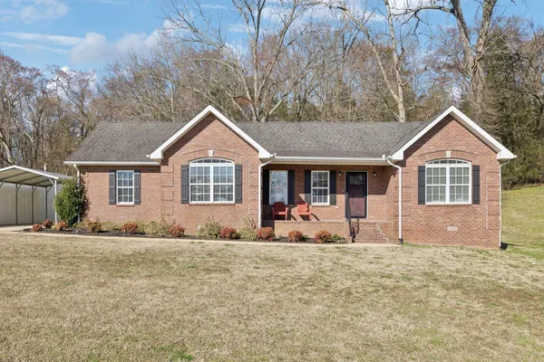 a front view of house with yard and trees in the background