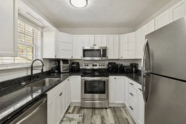 a kitchen with granite countertop a refrigerator stove and sink