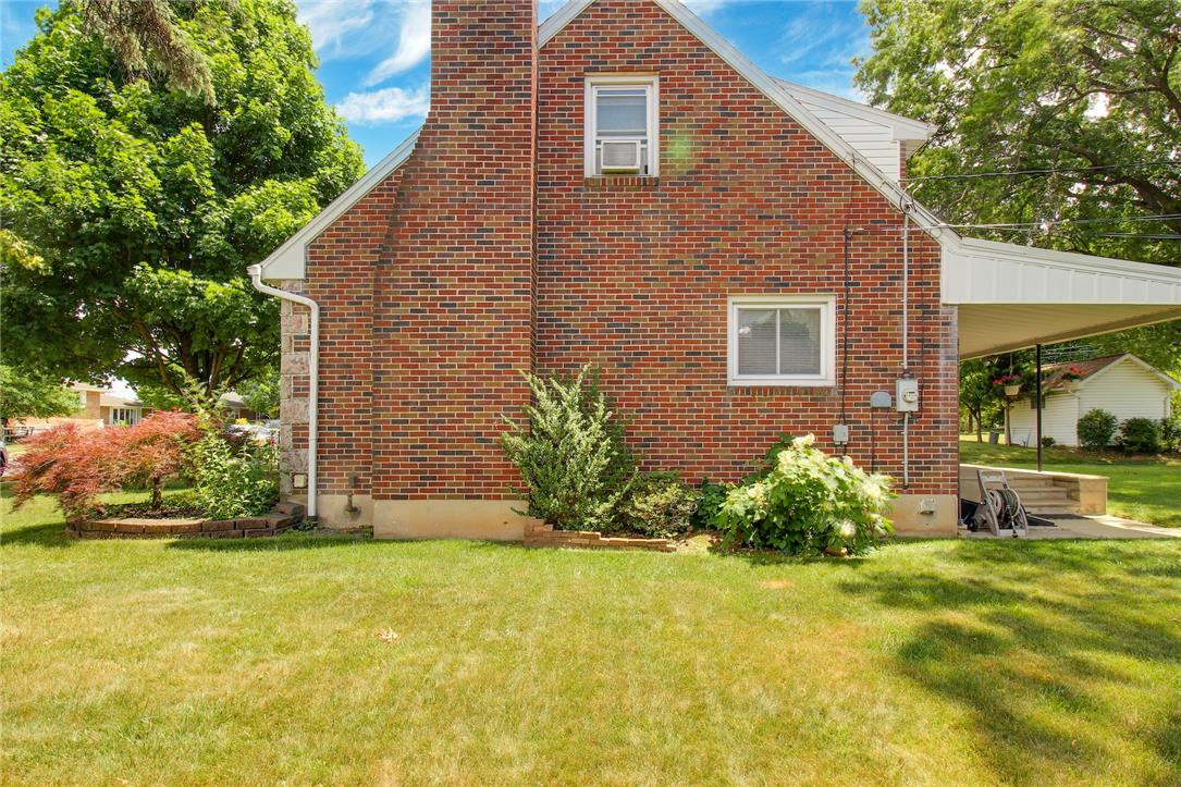1256 Ridge Avenue Whitehall, PA 18052 - Photo 6 of 43 Brick exterior home with lush green lawn, mature trees, and an inviting side porch.