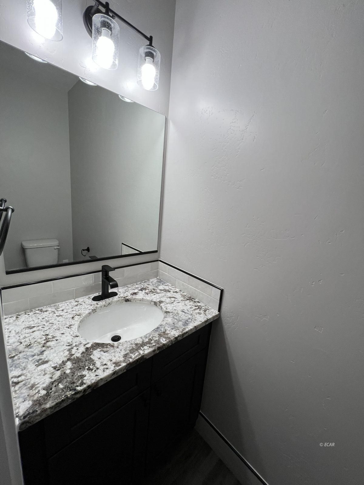 1265 Sun Vly Road Spring Creek, NV 89815 - Photo 23 of 34 a bathroom with a granite countertop sink and a mirror