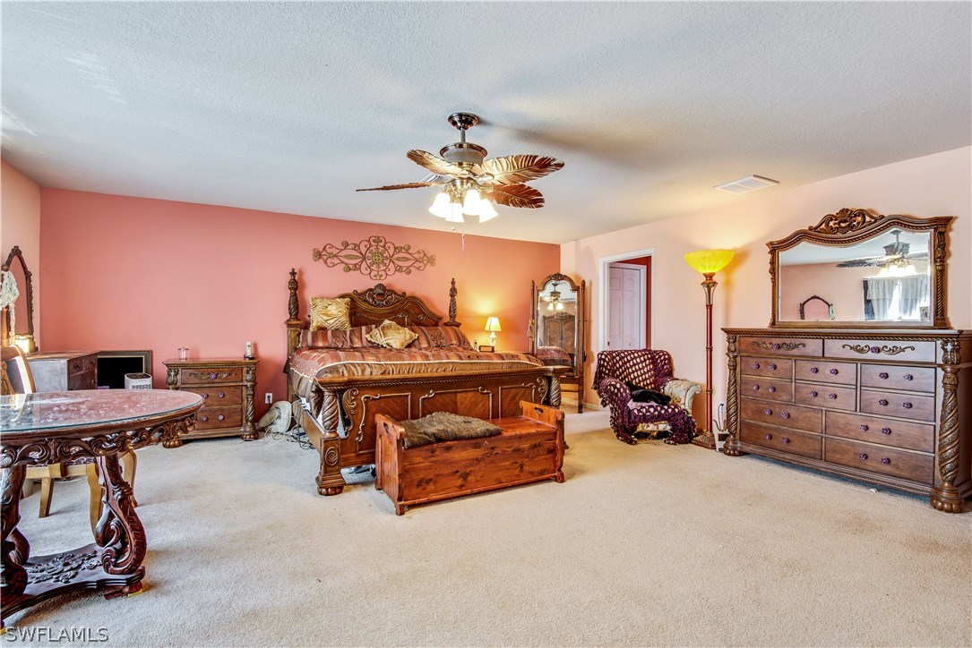 421 Jourferie Road Lehigh Acres, FL 33974 - Photo 14 of 25 a bedroom with furniture and a chandelier