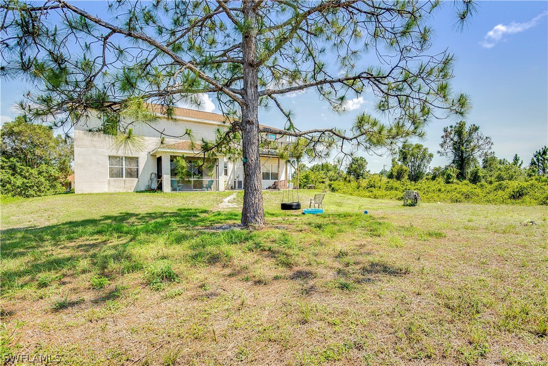421 Jourferie Road Lehigh Acres, FL 33974 - Photo 2 of 25 a view of a yard with plants and large trees