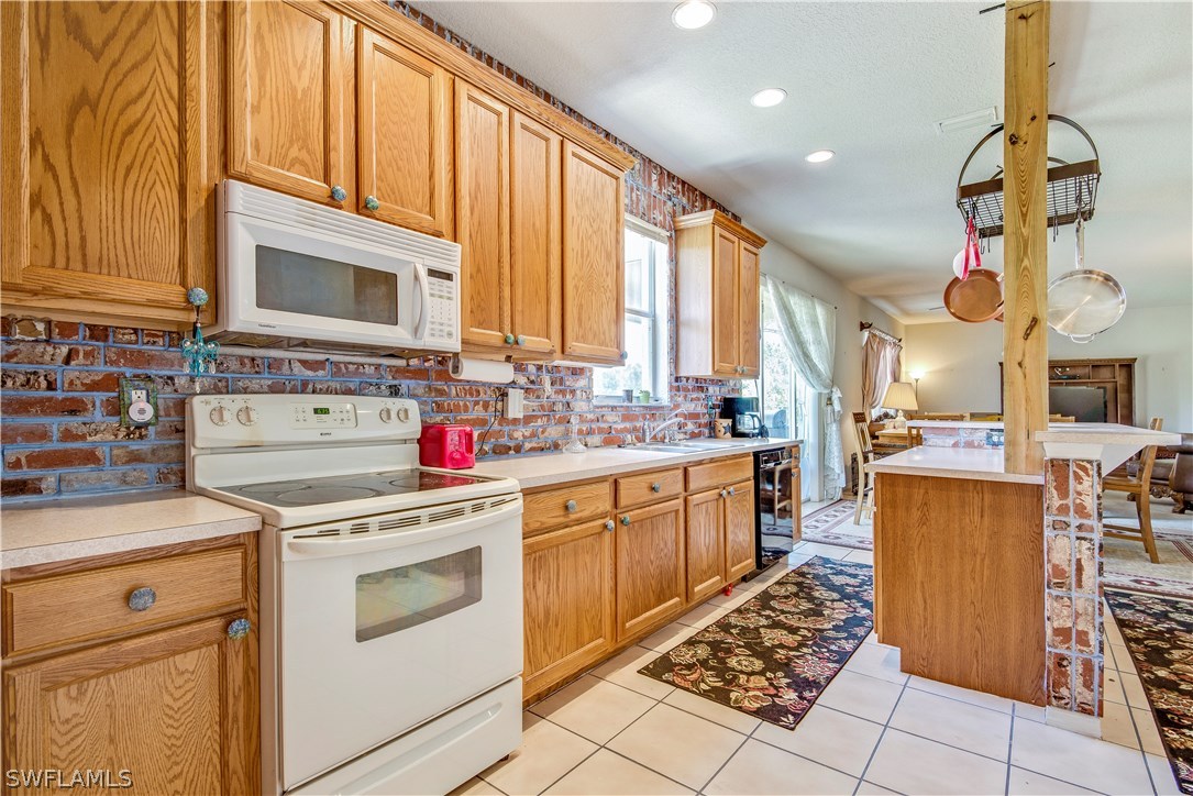 421 Jourferie Road Lehigh Acres, FL 33974 - Photo 7 of 25 a kitchen with a stove a sink dishwasher and white cabinets with wooden floor