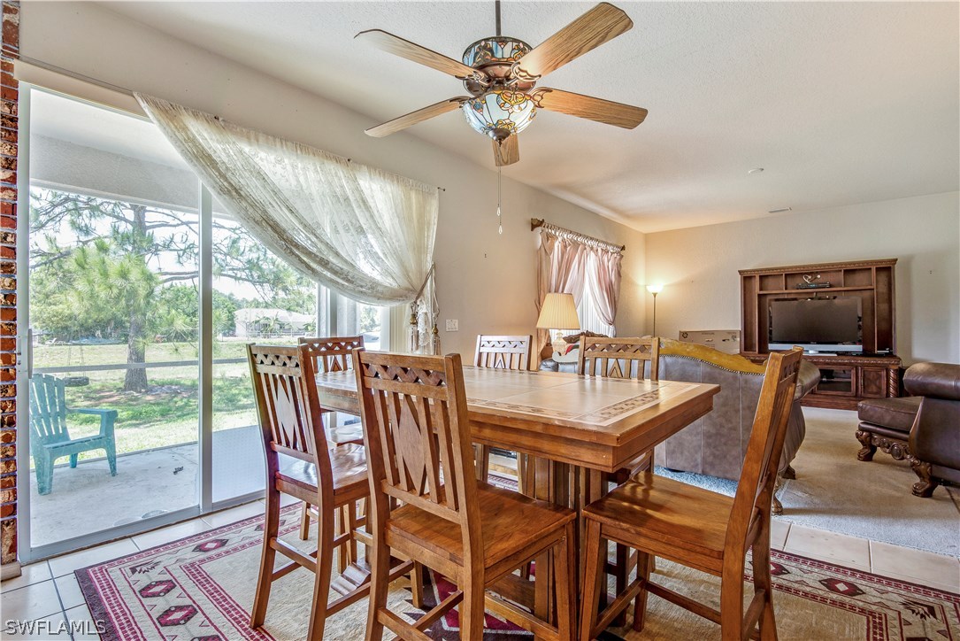 421 Jourferie Road Lehigh Acres, FL 33974 - Photo 10 of 25 a dining room with furniture a floor to ceiling window and a chandelier