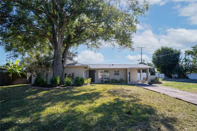 a view of a house with a big yard and palm trees