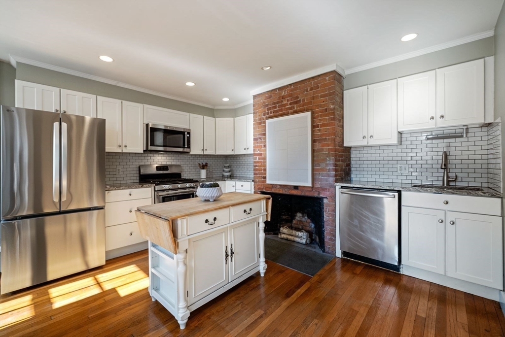 10 Summer Street, Unit 1 Boston, MA 02129 - Photo 9 of 37 a kitchen with white cabinets stainless steel appliances and wooden floor