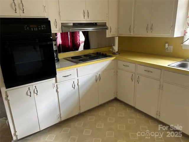 a kitchen with granite countertop white cabinets and black appliances