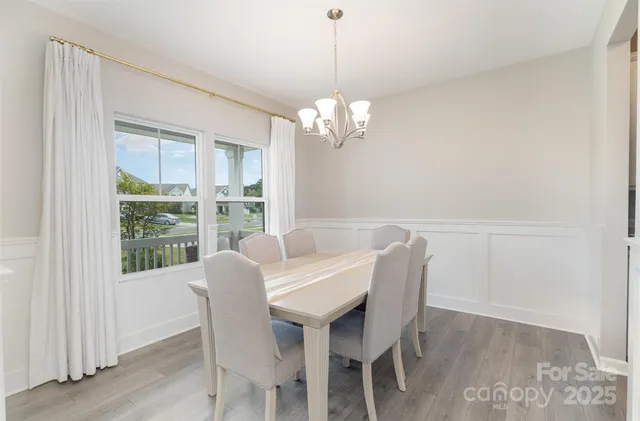 a dining room with wooden floor a chandelier a wooden table and chairs