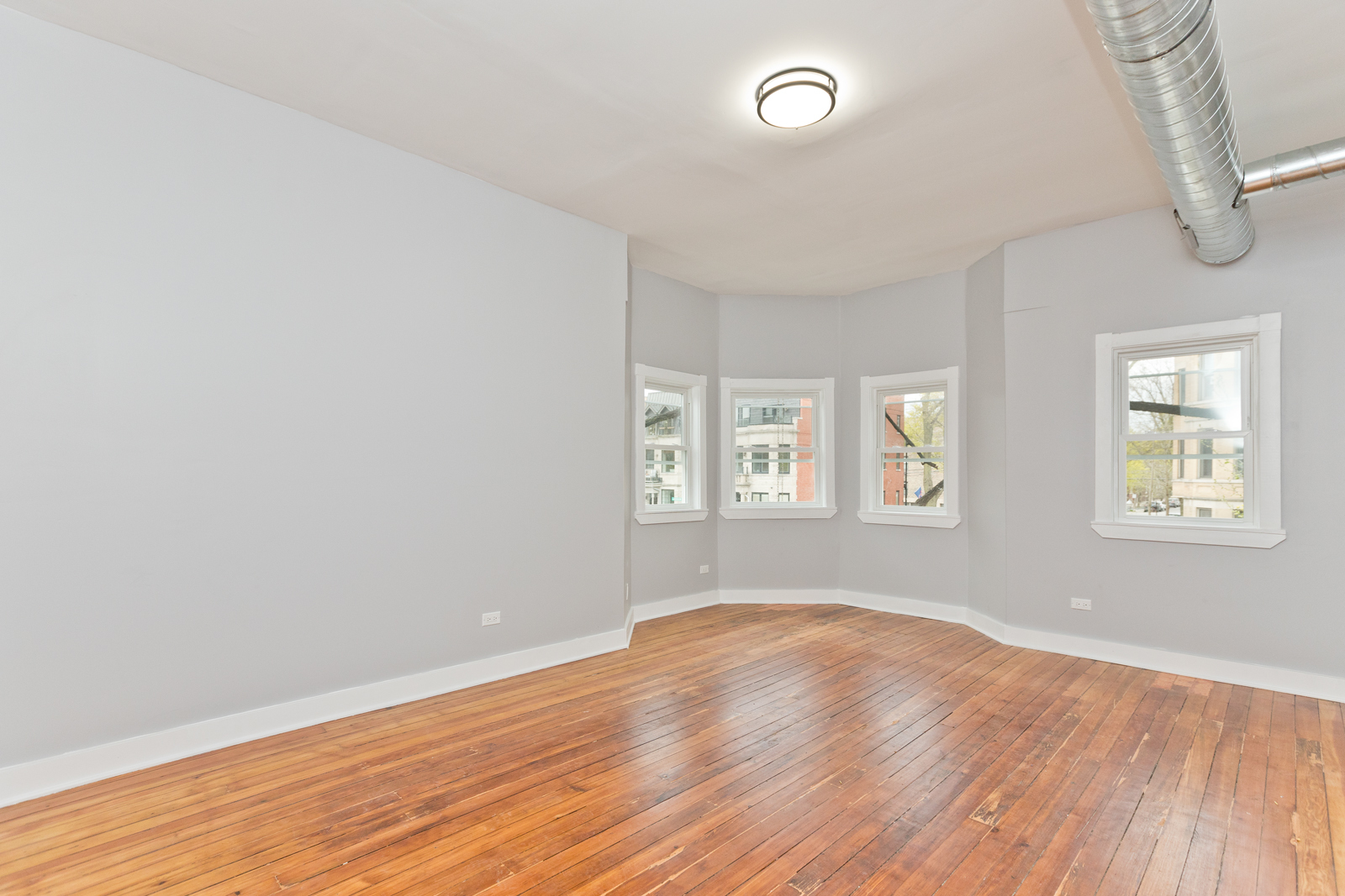 1300 West Addison Street, Unit 1 Chicago, IL 60613 - Photo 5 of 14 an empty room with wooden floor and windows