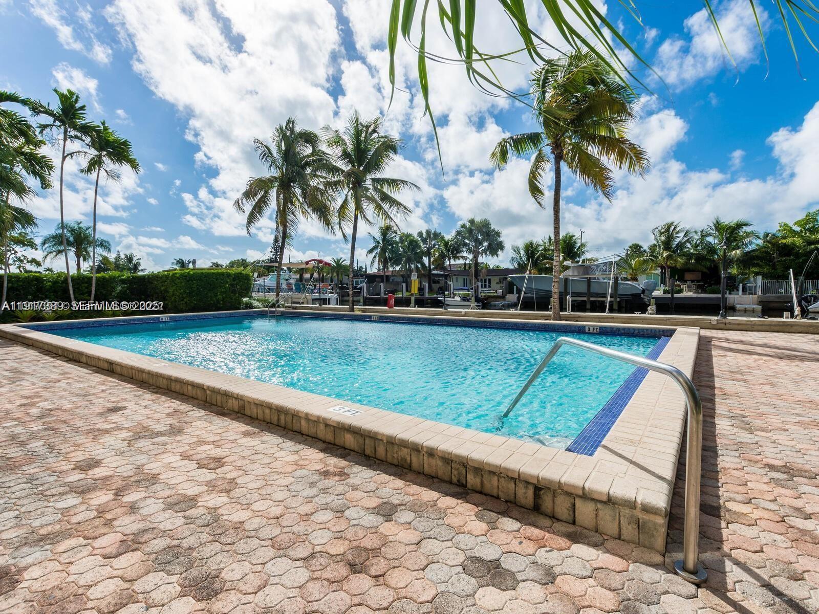 2350 Northeast 135th Street, Unit 1501 North Miami, FL 33181 - Photo 13 of 13 a view of swimming pool with a yard and palm trees
