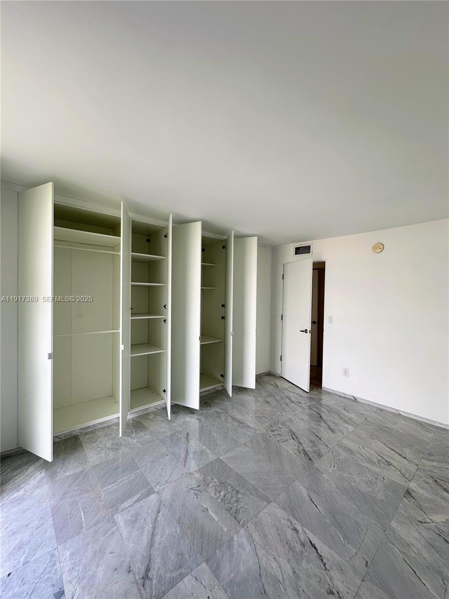 2350 Northeast 135th Street, Unit 1501 North Miami, FL 33181 - Photo 10 of 13 an empty room with closet and a large window