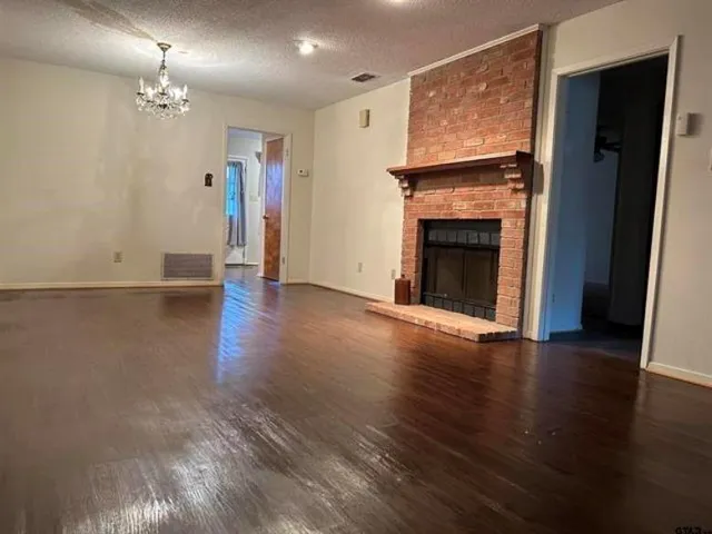 a view of a livingroom with wooden floor and a fireplace
