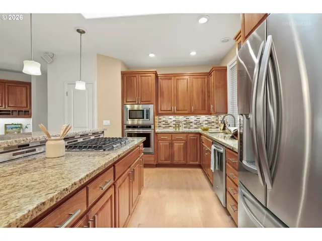 a kitchen with stainless steel appliances granite countertop a sink refrigerator and cabinets