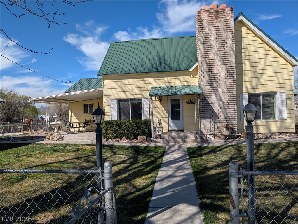 View of front of house featuring a fenced front yard, a metal roof, a gate, a chimney, and an attached carport