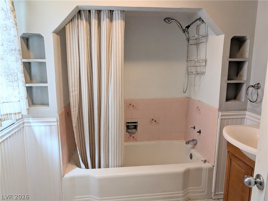 1 South 5th Street Panaca, NV 89042 - Photo 13 of 21 Bathroom with built in shelves, wainscoting, shower / tub combo, and vanity