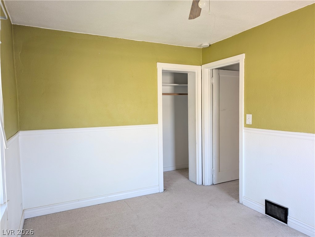 1 South 5th Street Panaca, NV 89042 - Photo 15 of 21 Unfurnished bedroom featuring light carpet, a closet, a ceiling fan, and a wainscoted wall