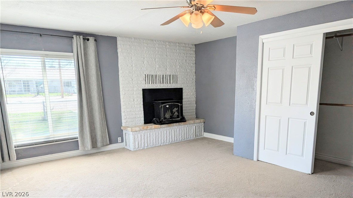 1 South 5th Street Panaca, NV 89042 - Photo 10 of 21 Primary bedroom featuring a ceiling fan, light carpet, and a built-in fireplace
