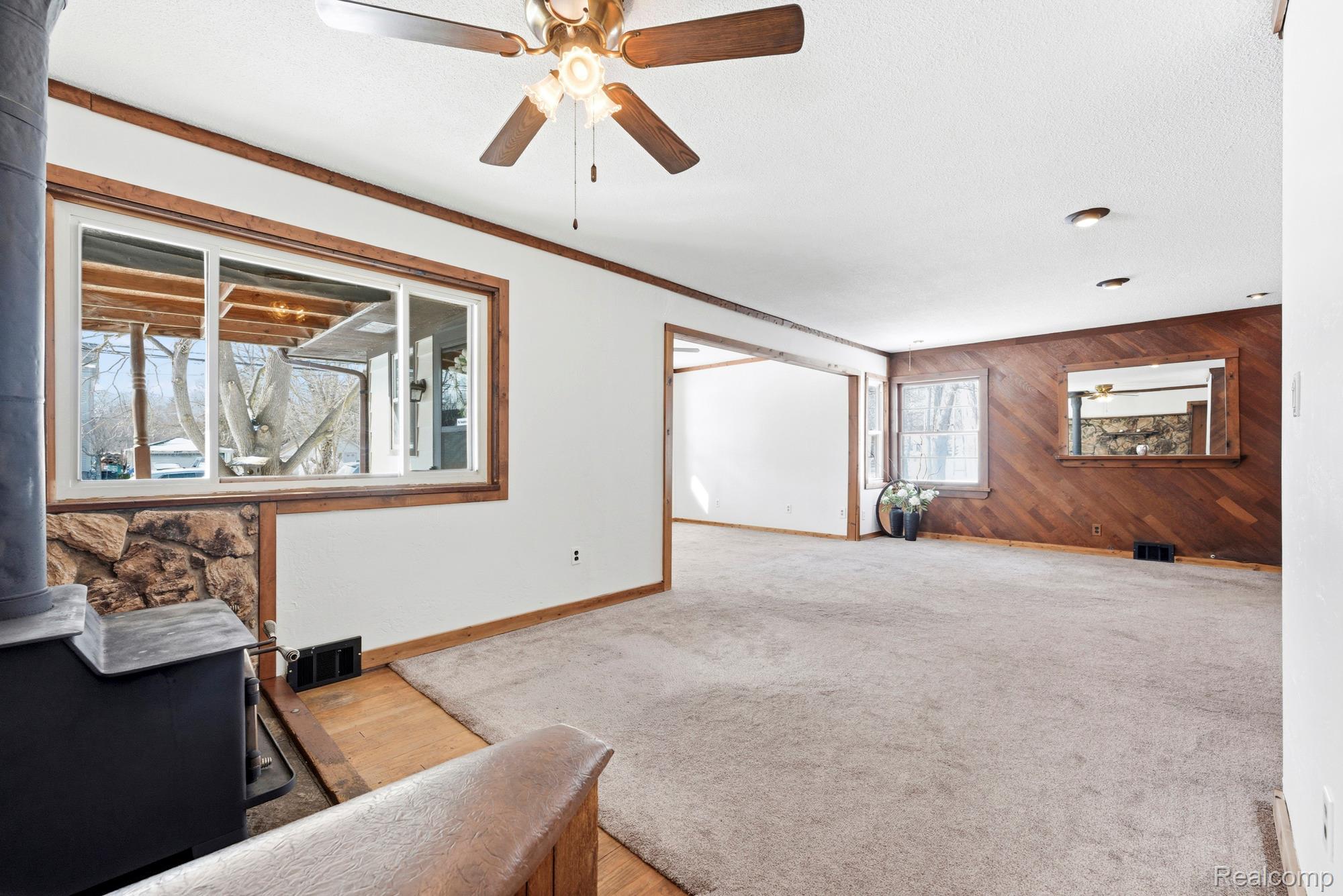 3375 Grant Road Rochester, MI 48309 - Photo 12 of 28 Unfurnished room featuring ceiling fan, wooden walls, ornamental molding, light colored carpet, and a textured ceiling