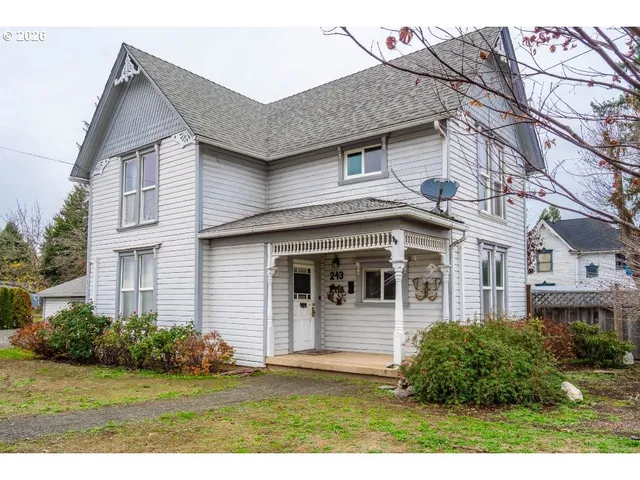 a view of a white house next to a yard with potted plants