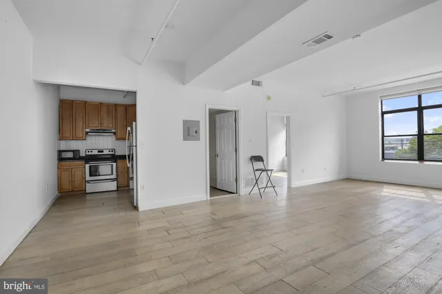 a view of empty room with kitchen and window