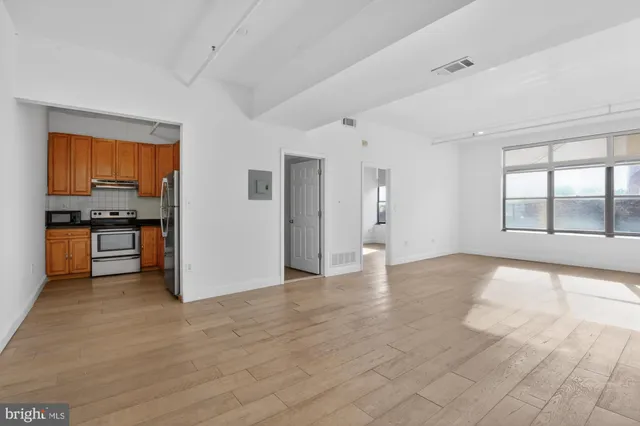 a view of an empty room with window and wooden floor