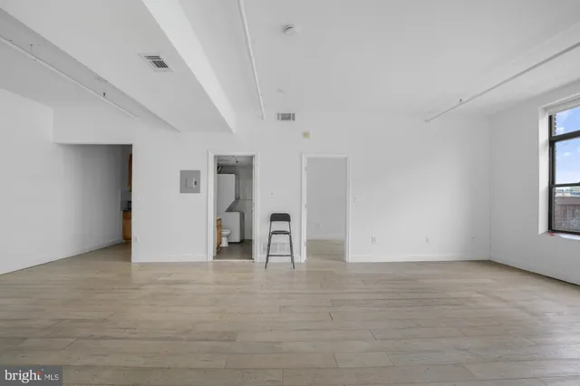 a view of empty room with window and wooden floor