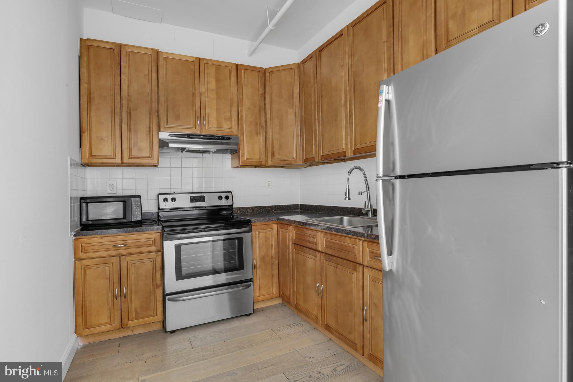 301 Spring Garden Street, Unit 3B Philadelphia, PA 19123 - Photo 8 of 22 a kitchen with a refrigerator sink and cabinets