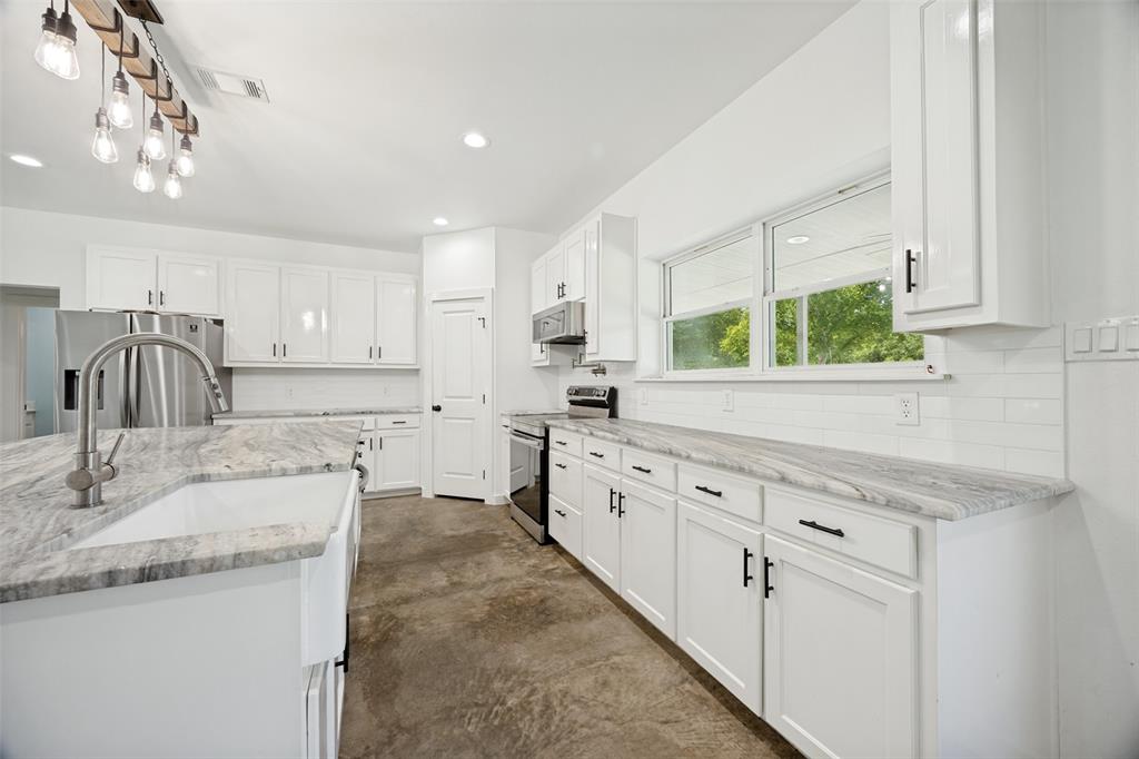 822 Private Road 7370 Point, TX 75472 - Photo 16 of 30 Bright kitchen featuring white shaker cabinetry, stainless steel appliances, a farmhouse sink with a gooseneck faucet, light-toned stone countertops, and a white subway tile backsplash