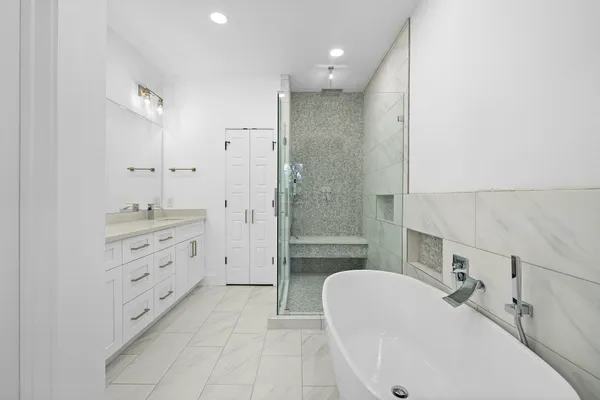 a bathroom with a tub sink double vanity and a mirror
