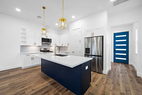 a kitchen with a sink stainless steel appliances and wooden floor