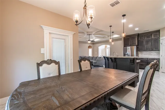 a kitchen with stainless steel appliances kitchen island granite countertop a table chairs refrigerator and cabinets