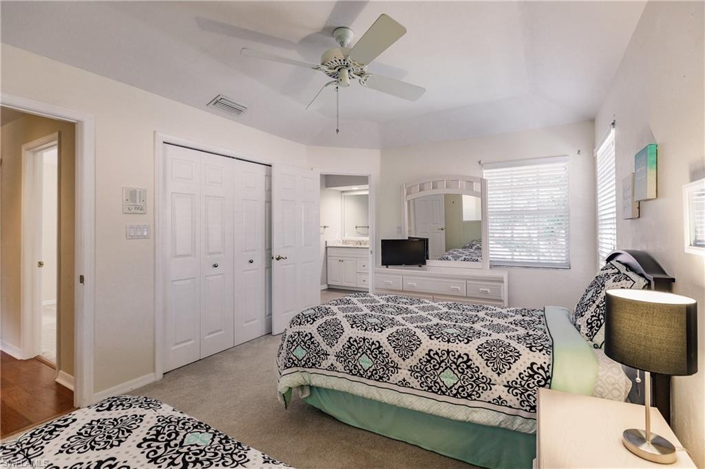 131 Napa Ridge Way Naples, FL 34119 - Photo 23 of 34 a bedroom with a bed and a chandelier