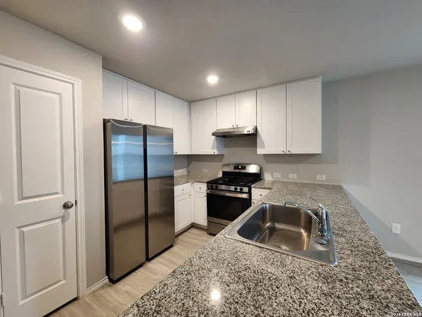 a kitchen with a refrigerator sink and cabinets
