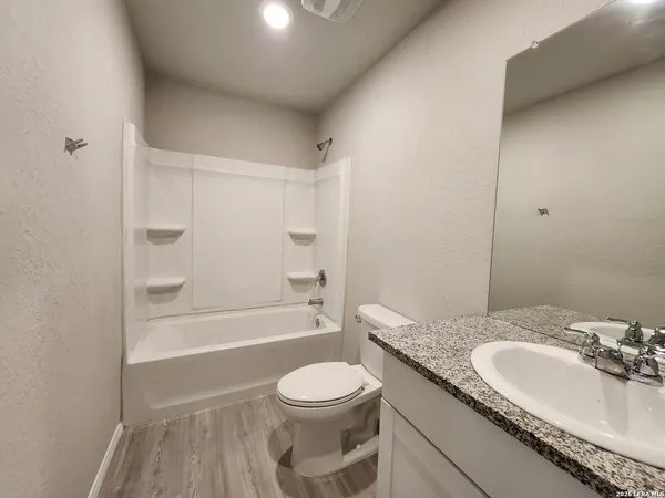 a bathroom with a granite countertop sink toilet a mirror and shower