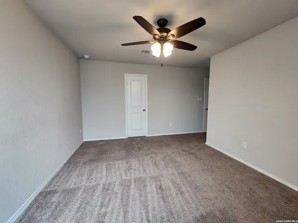an empty room with a chandelier fan and wooden floor