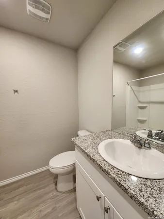 a bathroom with a granite countertop sink a toilet and a mirror
