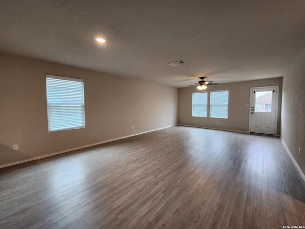 an empty room with wooden floor and windows