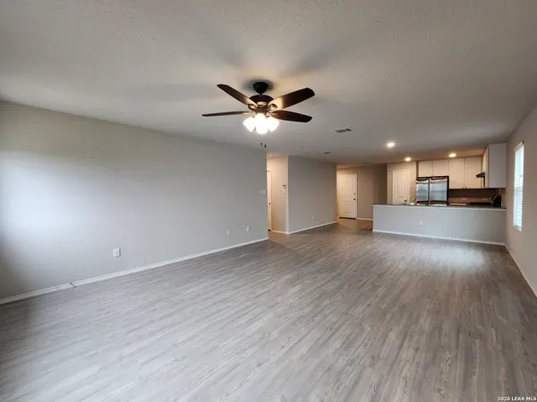 a view of an empty room with a ceiling fan and wooden floor