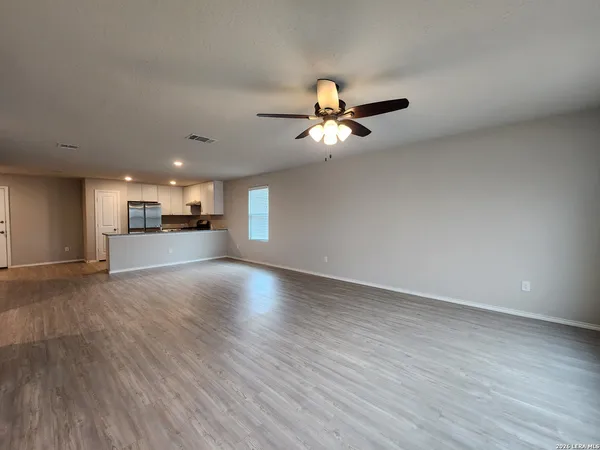 a view of an empty room with a kitchen and wooden floor