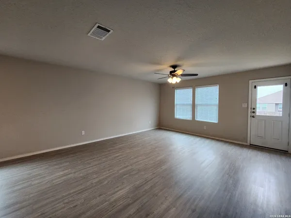 a view of an empty room with wooden floor and a window
