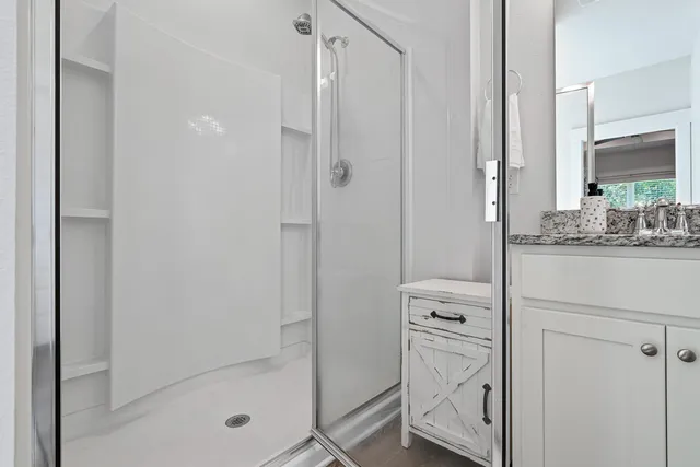 a spacious bathroom with a granite countertop sink a mirror and a shower