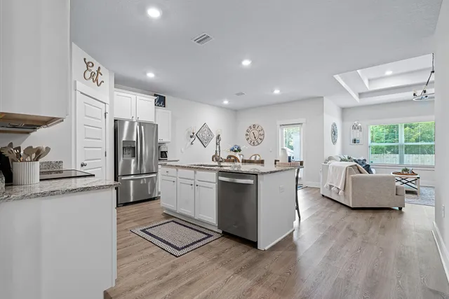 a kitchen with stainless steel appliances kitchen island granite countertop a sink and a refrigerator