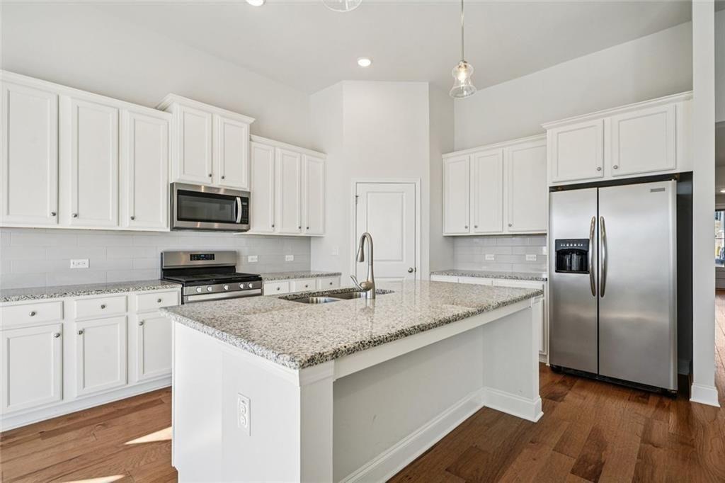 3431 High Shoals Buford, GA 30519 - Photo 13 of 51 a kitchen with stainless steel appliances granite countertop a sink a stove a refrigerator and white cabinets