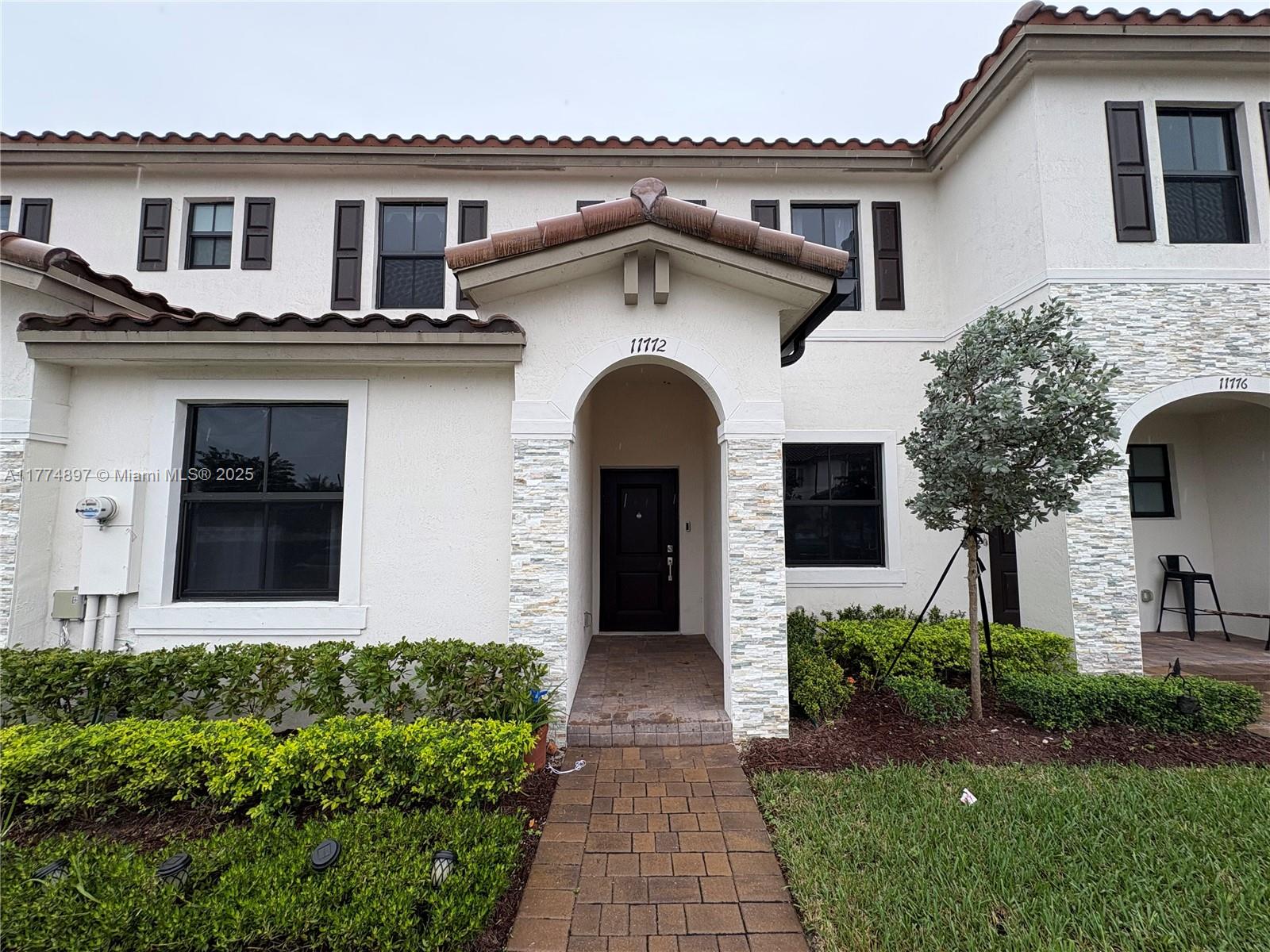11772 Southwest 247th Terrace, Unit 11772 Homestead, FL 33032 - Photo 1 of 27 a view of a white house with large windows and a small yard