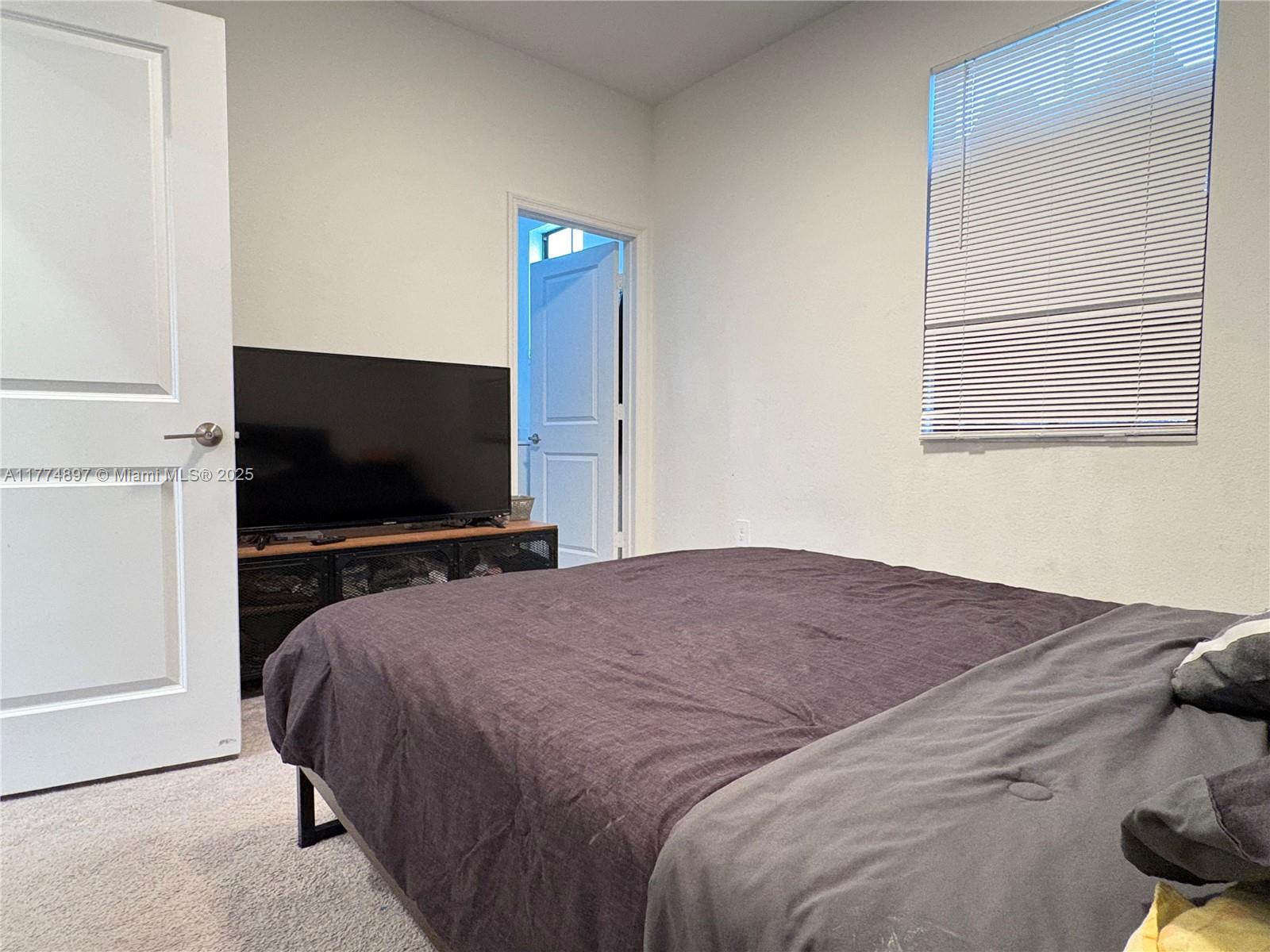 11772 Southwest 247th Terrace, Unit 11772 Homestead, FL 33032 - Photo 14 of 27 a bedroom with a bed and a flat screen tv
