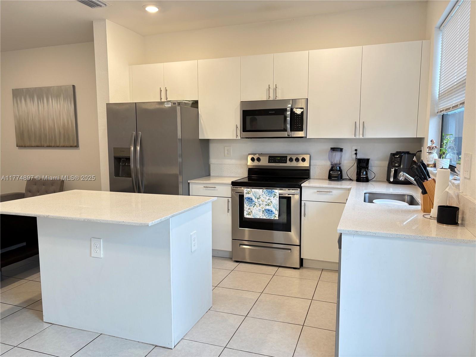 11772 Southwest 247th Terrace, Unit 11772 Homestead, FL 33032 - Photo 3 of 27 a kitchen with stainless steel appliances a refrigerator sink and microwave