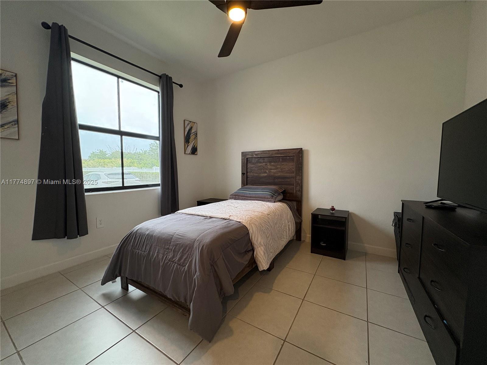 11772 Southwest 247th Terrace, Unit 11772 Homestead, FL 33032 - Photo 6 of 27 a bedroom with a bed and a television