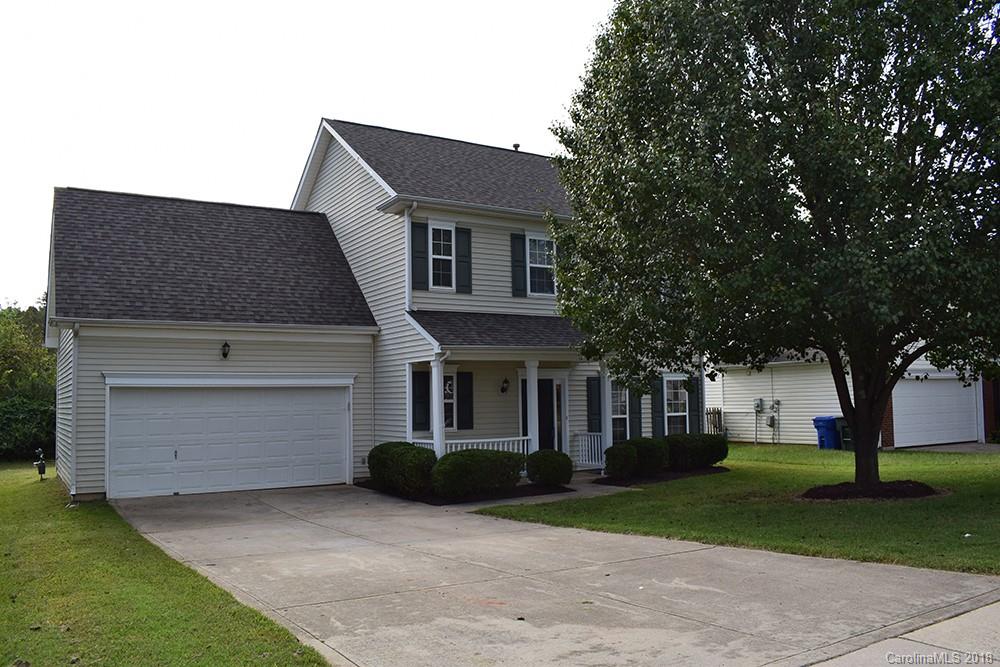 a front view of a house with a garden and trees